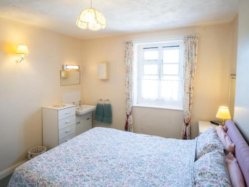 a bedroom with a bed and a window and a sink at Columbine Cottage in Ross on Wye