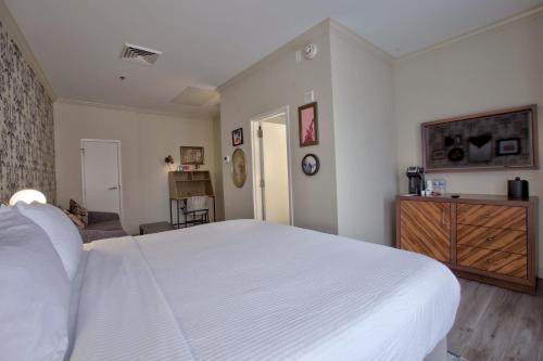 a bedroom with a white bed and a wooden dresser at Hotel Indigo - New Orleans - French Quarter in New Orleans