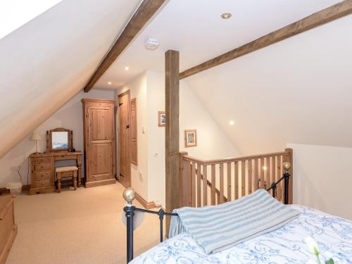 an attic bedroom with a bed and a staircase at Drovers Cottage in East Meon