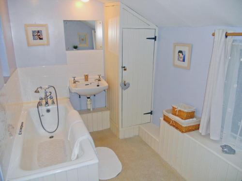 a bathroom with a tub and a sink and a bath tub at Fairmaiden in Polruan