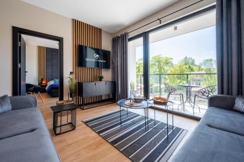 a living room with a couch and a glass table at Domki i apartamenty Skandynawia in Dąbki