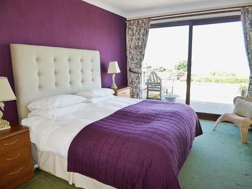 a purple bedroom with a bed and a window at The Beach House in Maidens
