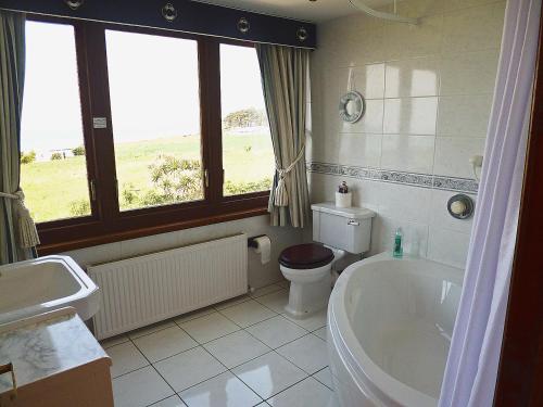 a bathroom with a tub and a toilet and a sink at The Beach House in Maidens