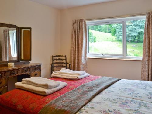 a bedroom with a bed with a dresser and a window at Bellegrove Cottage in Watermillock