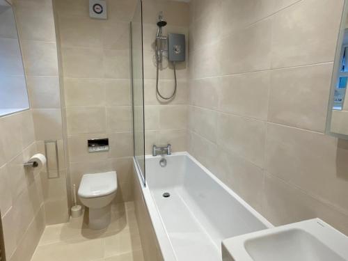a bathroom with a tub and a toilet and a shower at West View Cottage in Seahouses