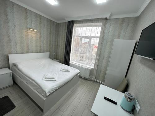 um pequeno quarto com uma cama e uma televisão em Hotel Elit em Ninotsminda