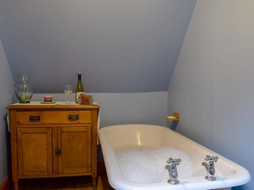 a white bath tub in a bathroom with wine glasses at Drummond Cottage in Kenmore