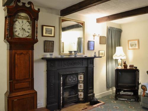 a grandfather clock in a living room with a fireplace at Bradley House in Harrop Fold