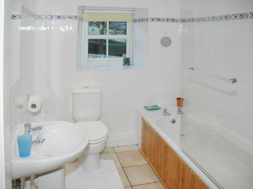 a white bathroom with a toilet and a tub and a sink at Chapelfield Cottage in Rosthwaite