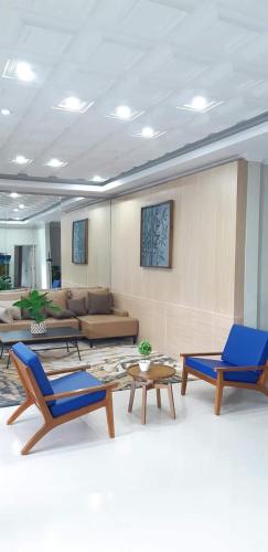 a living room with two blue chairs and a couch at Griya Sambilegi in Yogyakarta