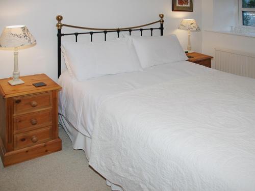 1 dormitorio con 1 cama blanca grande y 2 mesitas de noche en Chapelfield Cottage en Rosthwaite