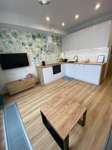a kitchen with white cabinets and a table in a room at Apartamenty Białe nad jeziorem Białym in Augustów