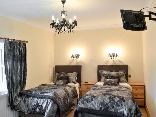 una camera con due letti e un lampadario a braccio di 4 Pengraig Draw a Llanychaiarn