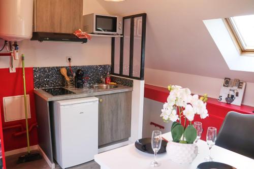 una pequeña cocina con mesa y fregadero en ROMANTIC STUDIO EVE - PROCHE GARE - NETFLIX - WiFi, en Amiens