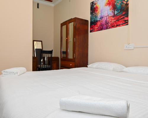 1 dormitorio con 2 camas blancas y una pintura en la pared en VIP GARDEN RESORT, en Varkala