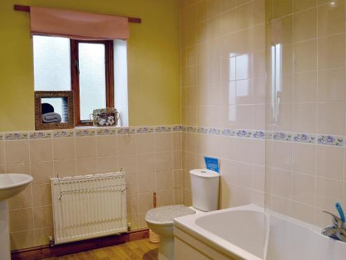 a bathroom with a toilet and a tub and a sink at Wykham in Nettleton