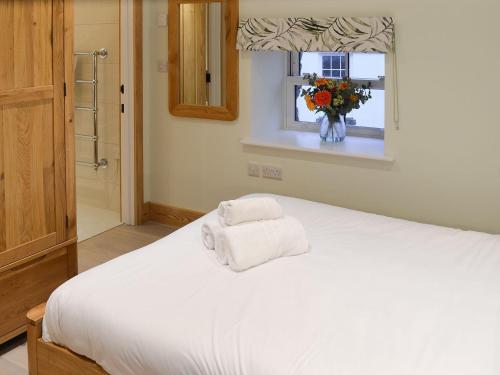Un dormitorio con una cama blanca con toallas. en Chancer, en Newlyn