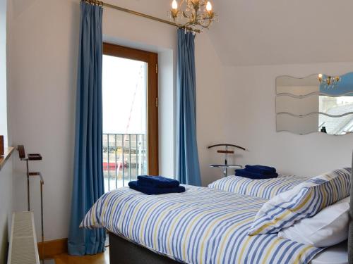 two beds in a room with blue curtains and a window at The Boathouse in Findochty