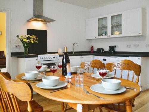 eine Küche mit einem Holztisch mit Gläsern Wein in der Unterkunft Glanmwrg Barn in Trostre