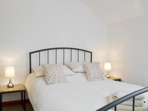 1 dormitorio con 1 cama blanca con almohadas y 2 lámparas en Ysgubor, en Tregarth