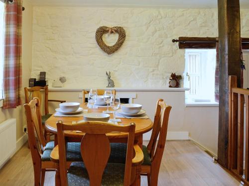 comedor con mesa de madera y sillas en Woodside Cottage en Auchnastank