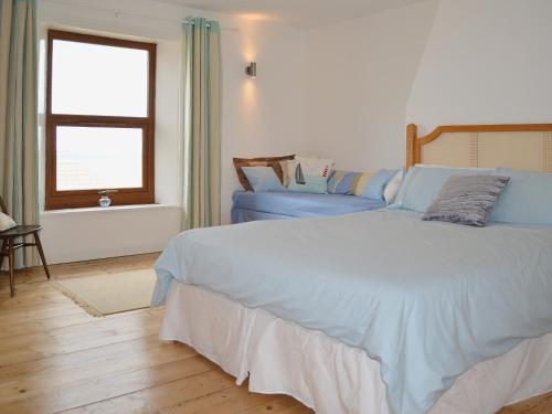 a bedroom with two blue beds and a window at Smugglers Lookout in Mundesley