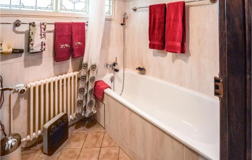 ein Badezimmer mit einer weißen Badewanne und roten Handtüchern in der Unterkunft Awesome Home In Knoeringue With Sauna in Knoeringue