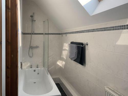uma casa de banho branca com um chuveiro e uma banheira em Granary em North Somercotes