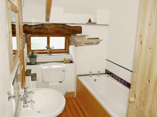 a bathroom with a toilet and a tub and a sink at Well Barn in Lanteglos