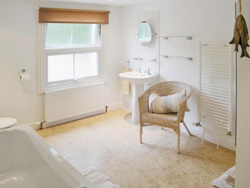 a bathroom with a sink and a chair and a tub at Willow Cottage in Corpusty