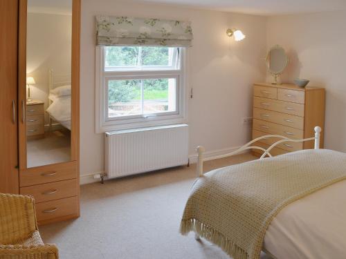 a bedroom with a bed and a window and a dresser at Willow Cottage in Corpusty