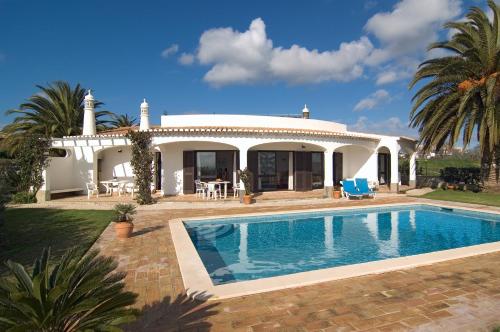 a villa with a swimming pool in front of a house at Villa Camena, private pool, sea view, residential area outside of the village Praia da Luz in Luz