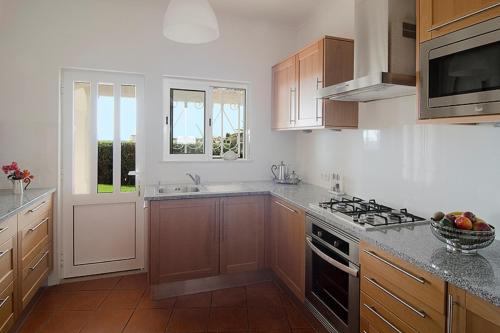 a kitchen with wooden cabinets and a stove top oven at Villa Camena, private pool, sea view, residential area outside of the village Praia da Luz in Luz
