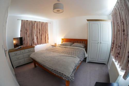 a bedroom with a bed and a cabinet and a television at Self contained Stylish 3 Bed Home in Great Plumstead