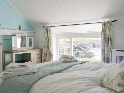 a bedroom with a bed with a large window at Bwthyn Y Borth in Rhoscolyn