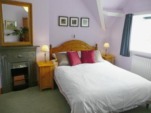 a bedroom with a bed with white sheets and red pillows at Gardeners Cottage in Watermillock