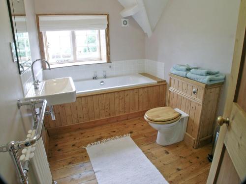 uma casa de banho com uma banheira, um WC e um lavatório. em Gardeners Cottage em Watermillock