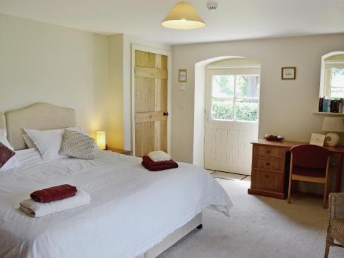 a bedroom with a white bed and a desk and a window at Rose Cottage in Rillington