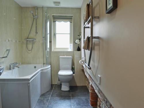 a bathroom with a toilet and a tub and a sink at Rose Cottage in Rillington