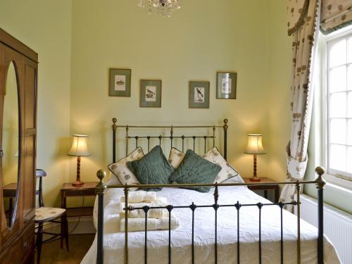a bedroom with a bed with green walls and two lamps at Cutcliffe Chambers - Hppr in Bideford