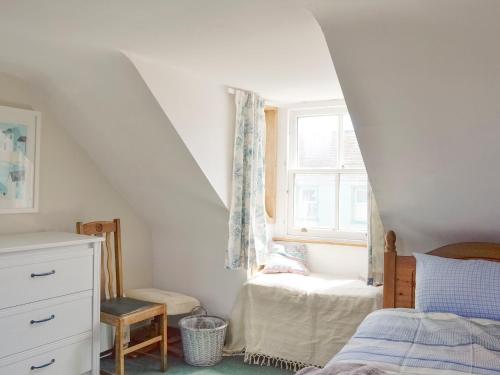 a attic bedroom with a bed and a window at Mill Street in Drummore