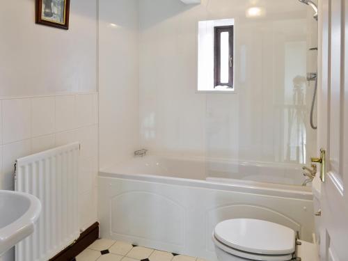 a white bathroom with a toilet and a sink at Farlam House Barn in Farlam