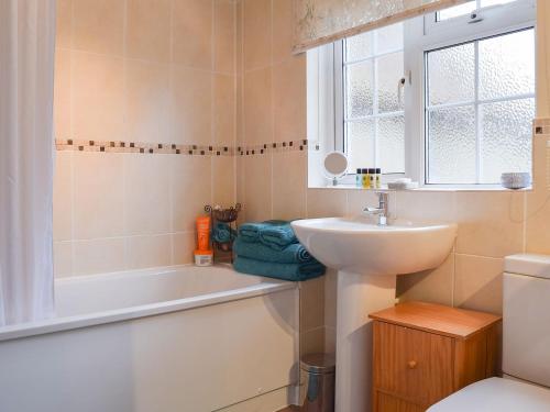 a bathroom with a sink and a tub and a toilet at Westover Cottage in Wootton