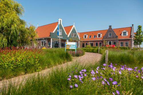 un jardín con flores púrpuras frente a un edificio en Comfort Rooms & Appartments by EuroParcs Poort van Amsterdam, en Uitdam