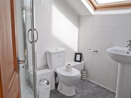 a white bathroom with a toilet and a sink at Gwelfor in Trearddur