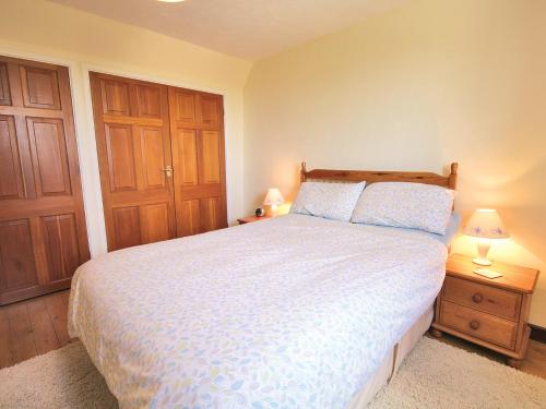 a bedroom with a bed and two wooden cabinets at Fox Cottage - E4510 in Chipping Sodbury