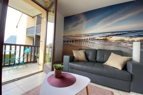 un soggiorno con divano e un dipinto della spiaggia di Quiet apartment with balcony near the sea a Ouistreham