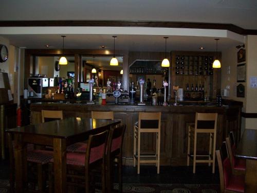 a bar in a restaurant with a table and chairs at The Fitzwilliam Hotel in Rotherham