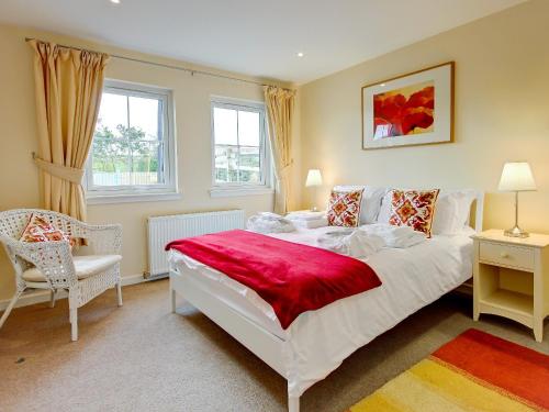 a bedroom with a large white bed and a chair at Barn Owl Cottage - 27941 in Cambusbarron