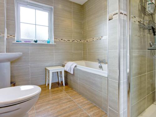 a bathroom with a tub and a toilet and a sink at Barn Owl Cottage - 27941 in Cambusbarron